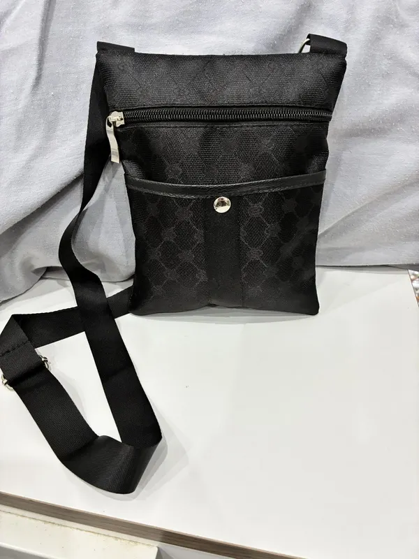 Flat crossbody bag crafted from durable black nylon canvas woven strap